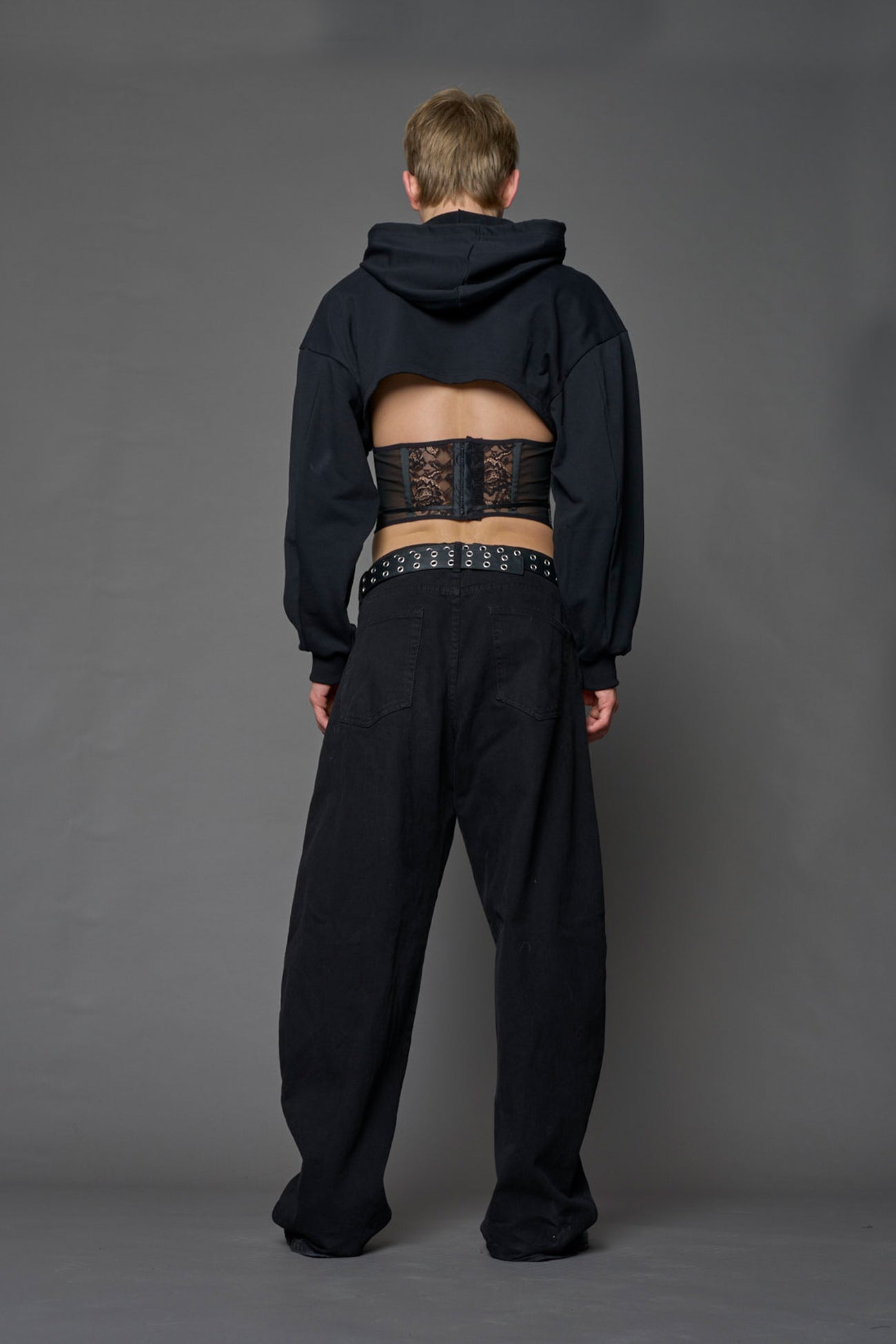 male model wearing a lingerie-inspired black hoodie with a lace corset