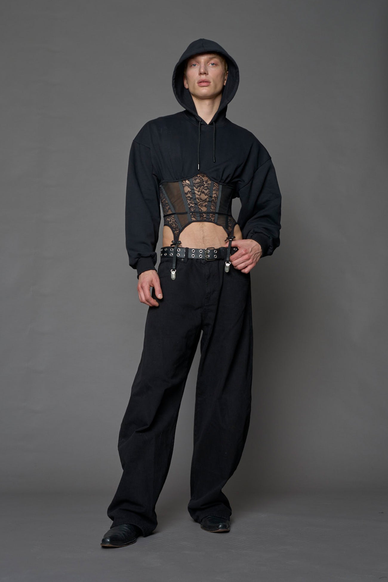 male model wearing a lingerie-inspired black hoodie with a lace corset