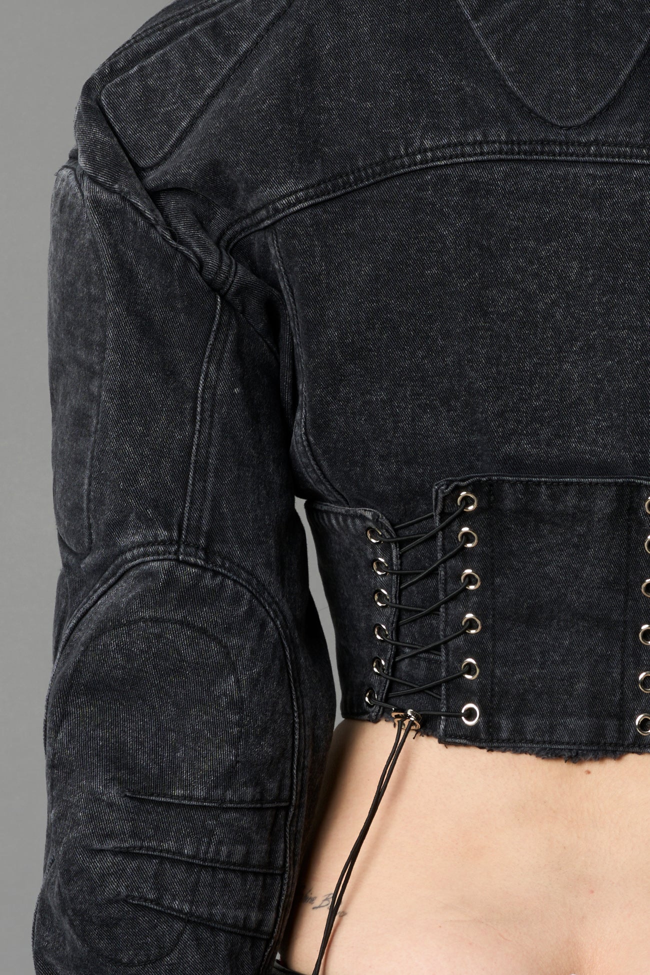 model wearing black washed denim jacket with structured corset waist and moto-style silhouette