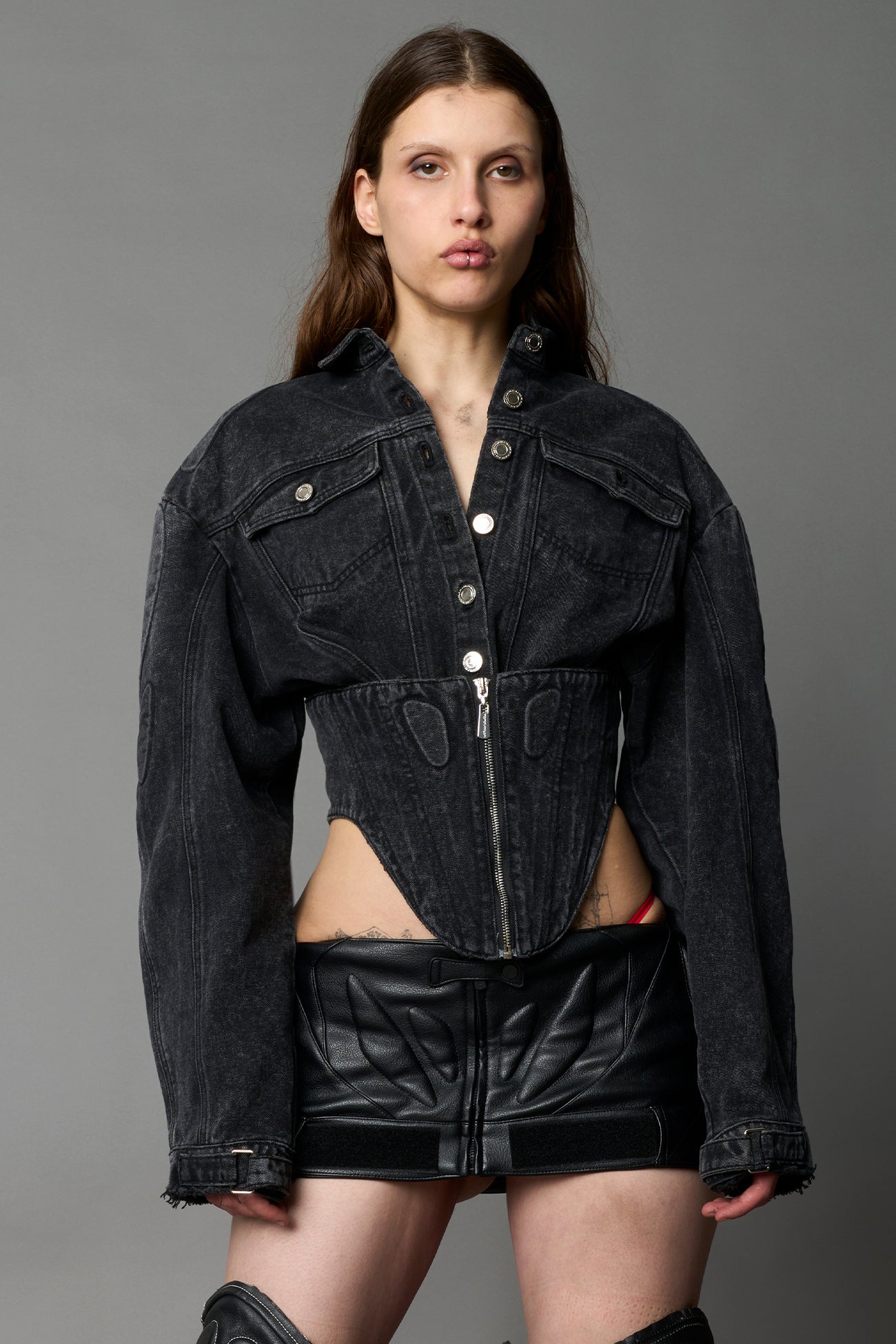 model wearing black washed denim jacket with structured corset waist and moto-style silhouette