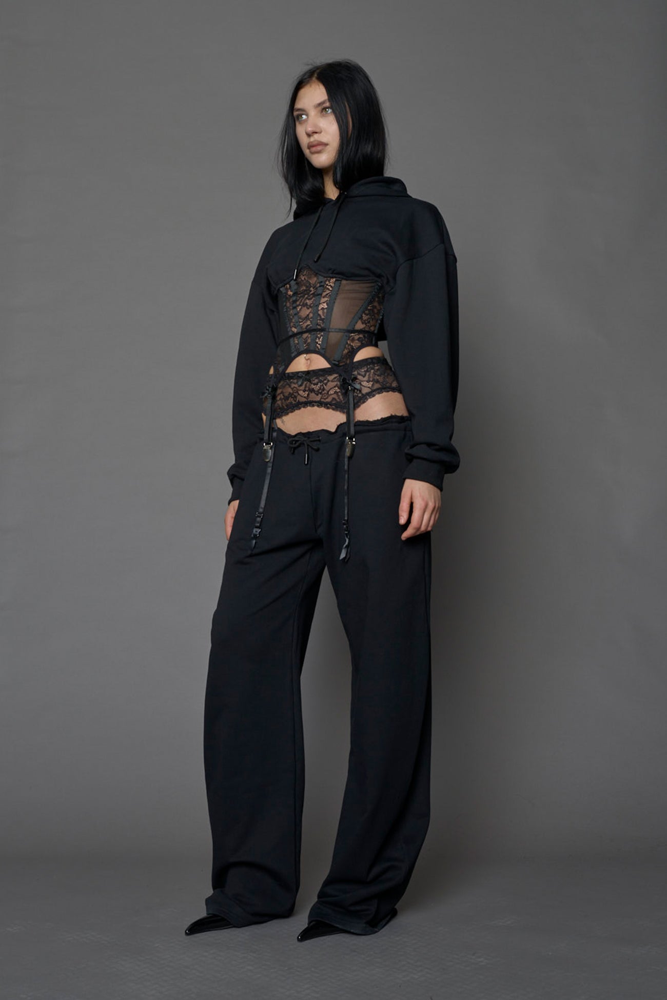 female model wearing a black low waist jogger with a lace suspender belt
