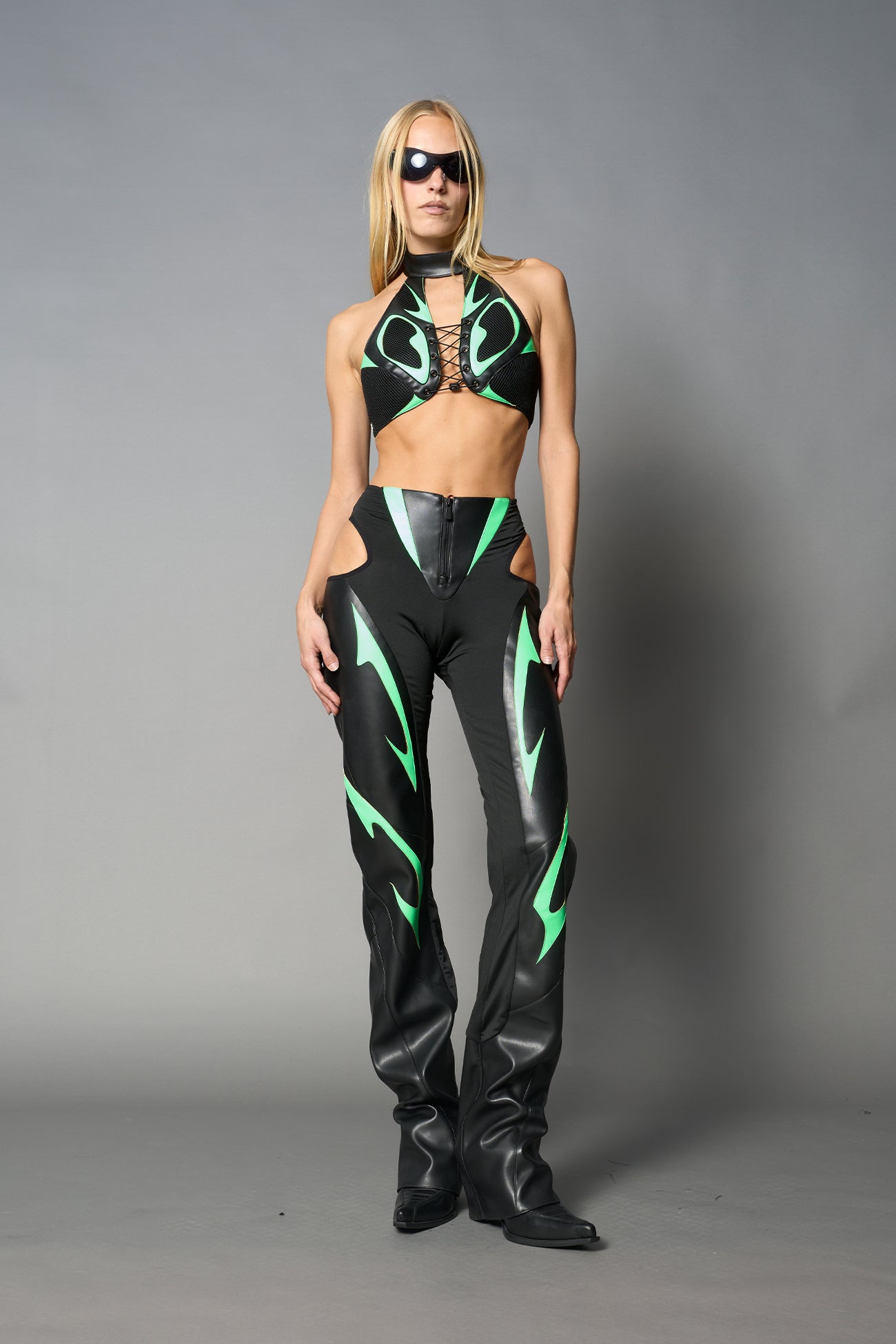Green vegan leather neckholder crop top with lace-up front, high neck collar, and mesh panel detailing – edgy moto-inspired top for clubwear or streetwear.
