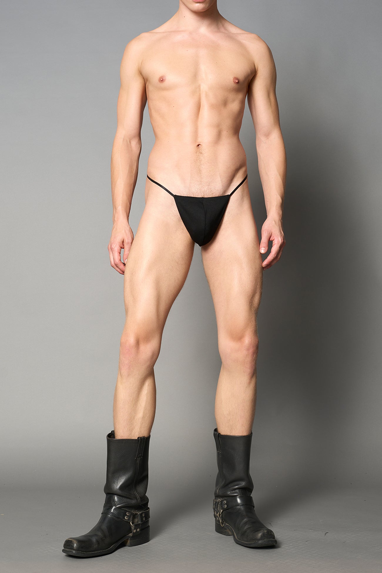 model wearing black thong with metal crucifix back