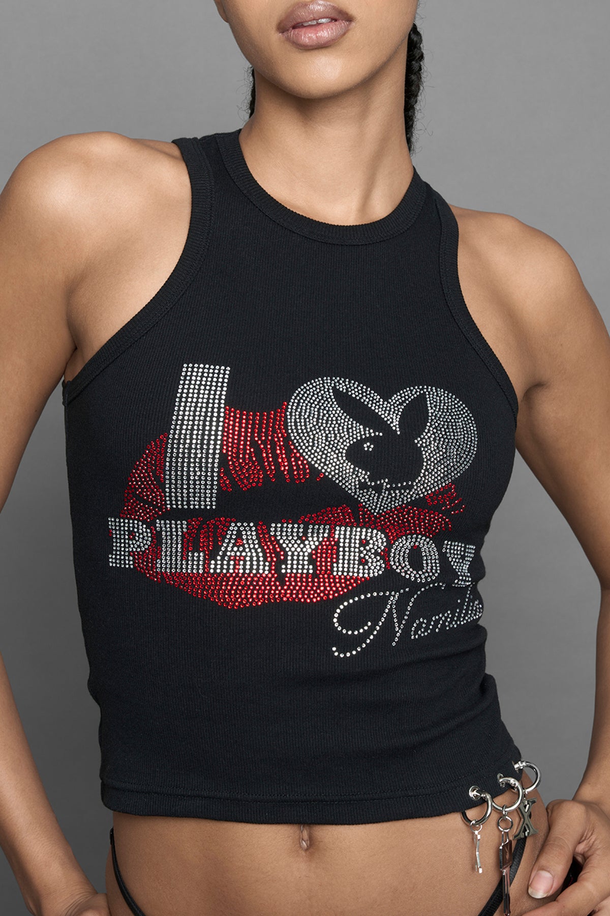 A model wearing a black halter crop top with red and silver 'I <heart> PLAYBOY Namilia' graphic, paired with black pants featuring a red lip print