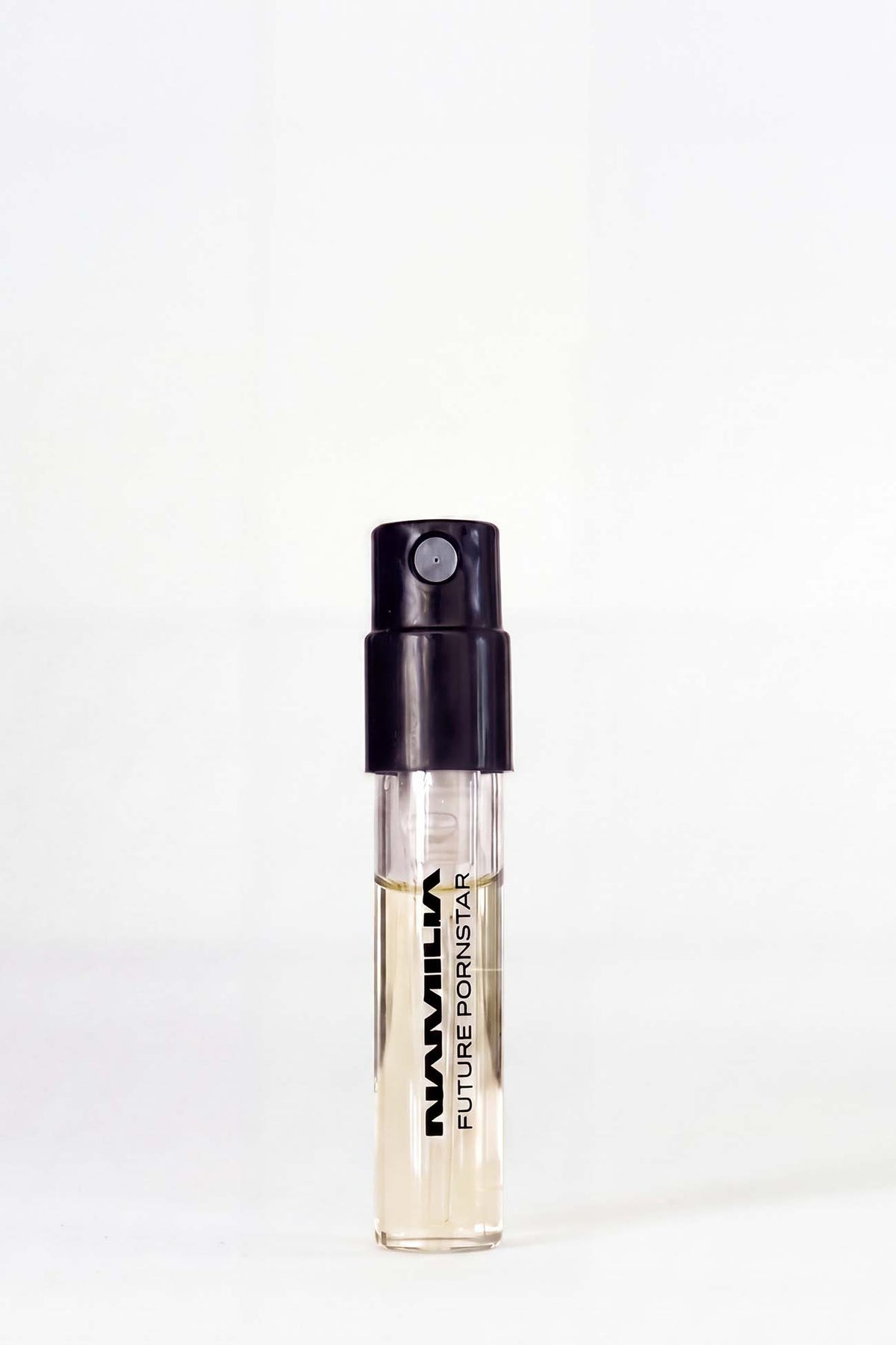 A bottle of Namilia Concrete CO2 Eau de Parfum with a large reflective black plug-shaped cap