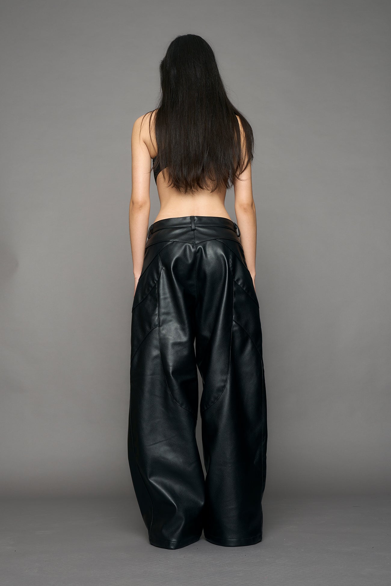 model wearing black oversize pu leather pants with moto style highlights