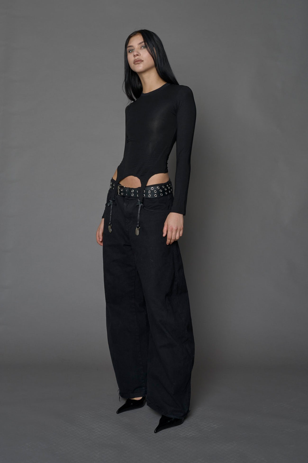 Female model wearing a form fitted lingerie-inspired black longsleeve with garter belt detail