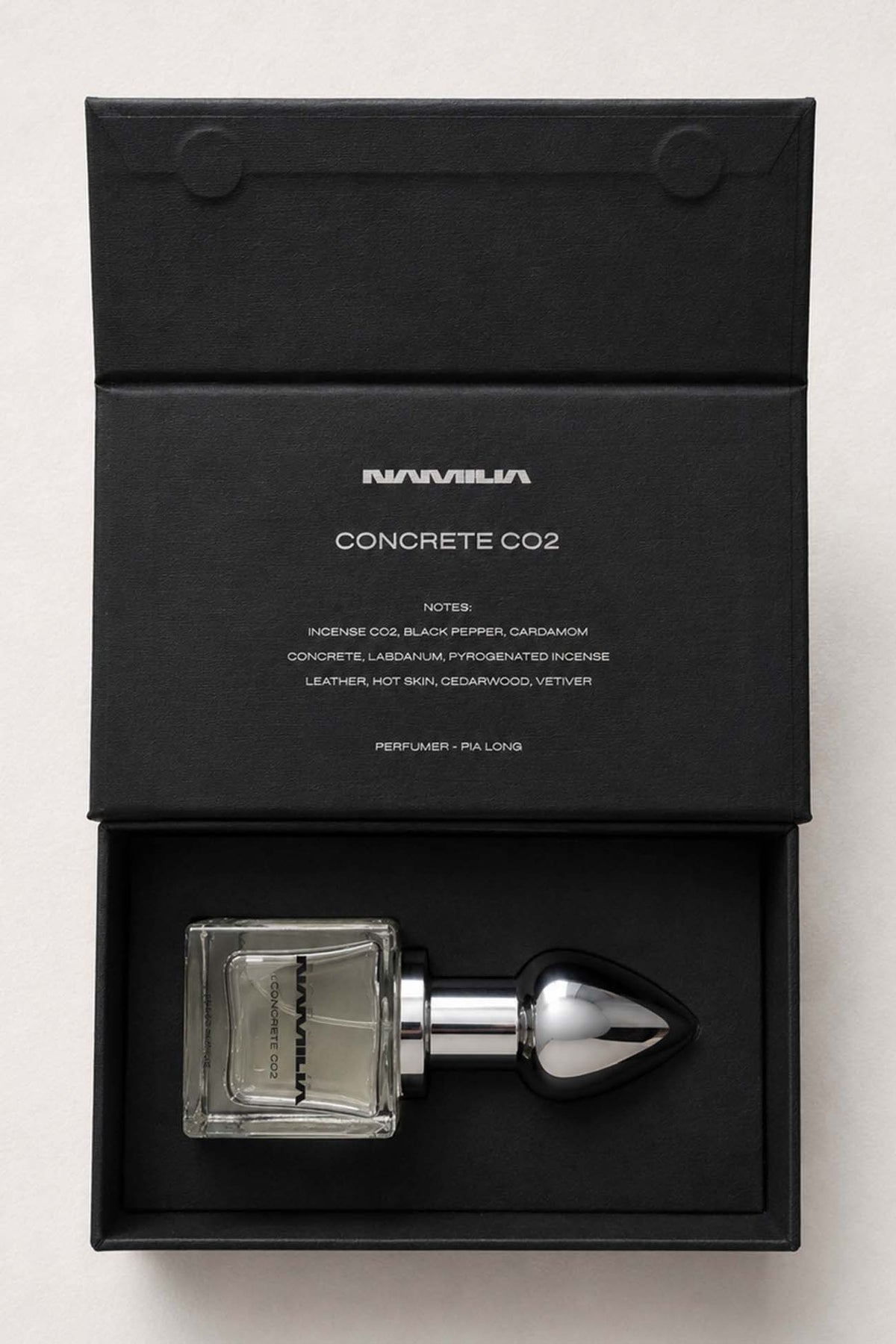 A bottle of Namilia Concrete CO2 Eau de Parfum with a large reflective black plug-shaped cap