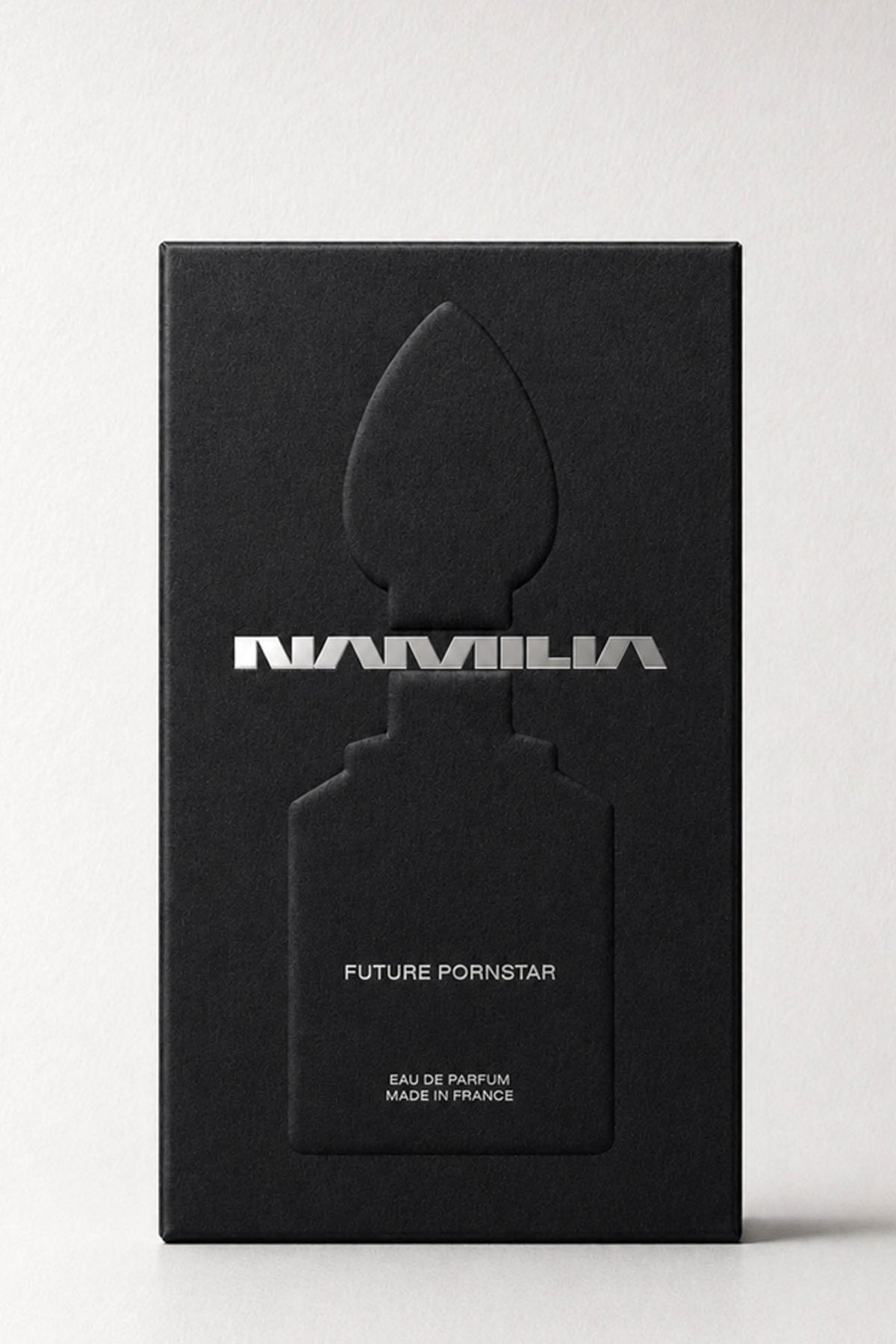 A bottle of Namila  Eau de Parfum with a large reflective plug-shaped cap inside the box