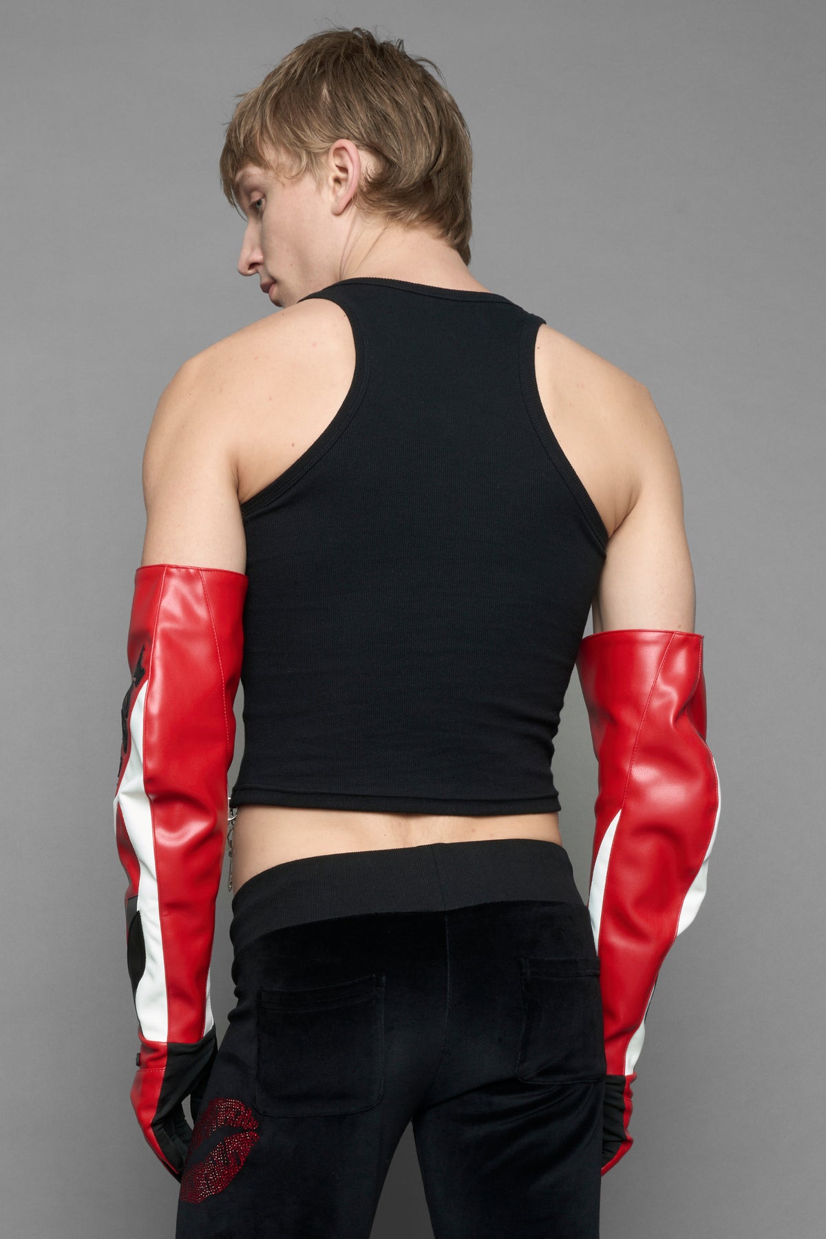 A model wears long motocross inspired red vegan Leather gloves with white and grey style paneling and black PU Leather 'Namilia' and 'Playboy' embroidery and a 'Playboy x Namilia' Rubbertag.