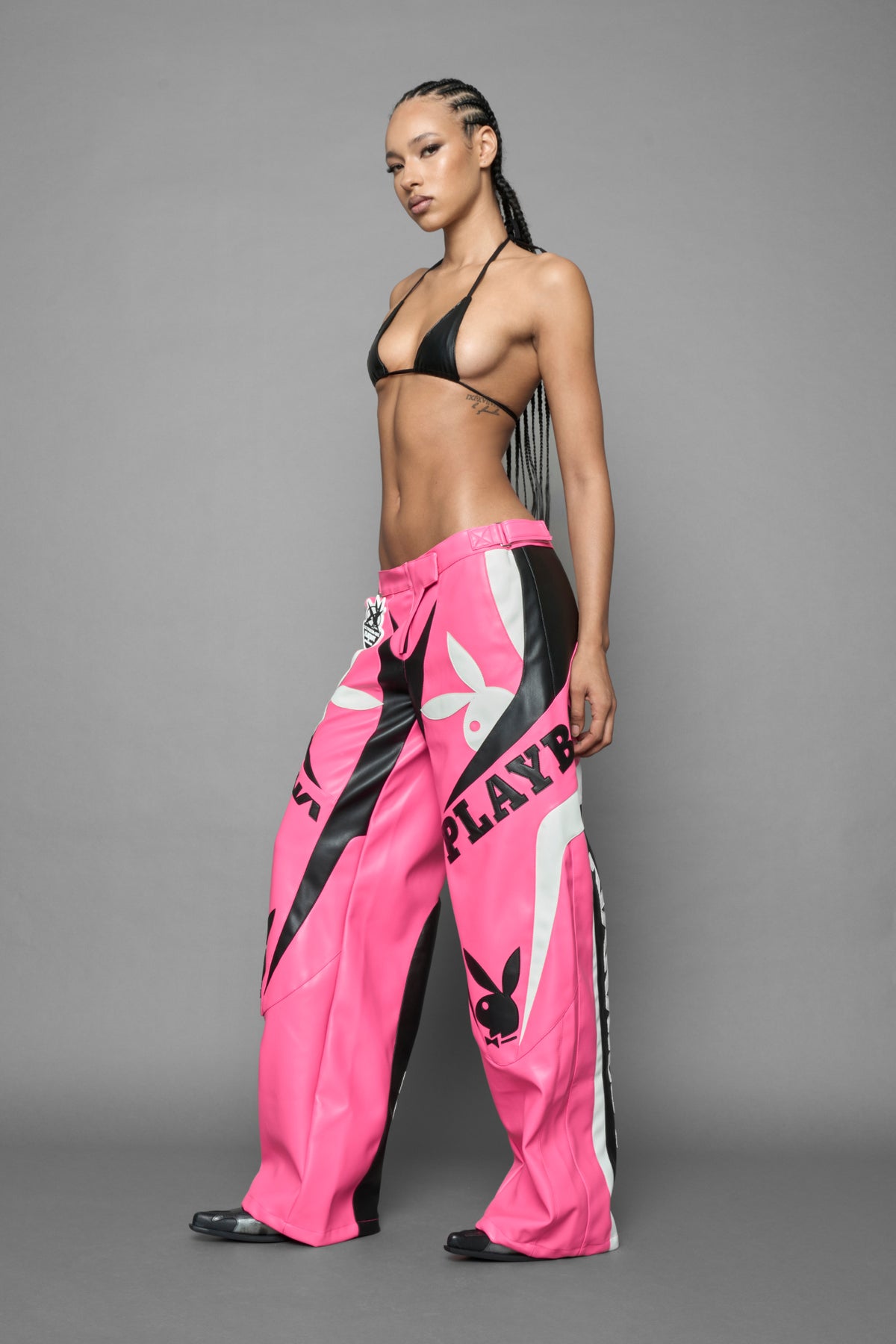 model is wearing pink PU Leather pants with bold white Playboy bunny logos and white 'Namilia' Embroidery and rubber tag.